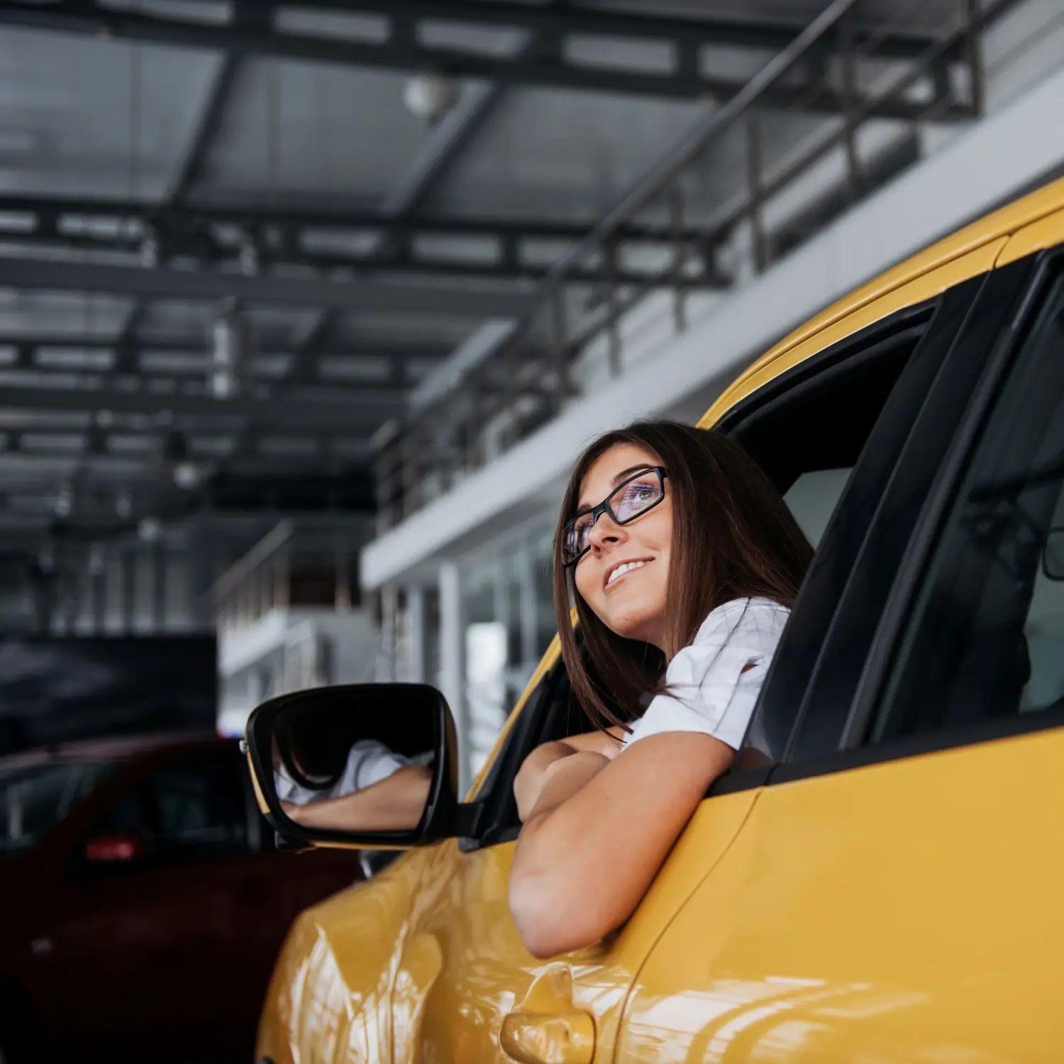smiling-woman-inside-a-yellow-car-looking-up-2026-01-09-00-39-43-utc.webp